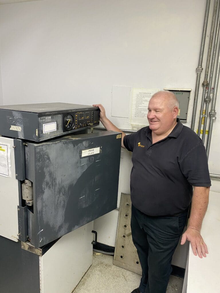 Priorclave UK Sales Director Lee Oakley standing with an early Priorclave autoclave, which has been reliably chugging away for 27 years.